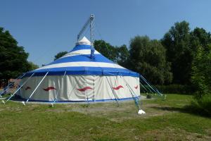 aufgebautes Zirkuszelt auf einer Wiese in Saalenaehe 